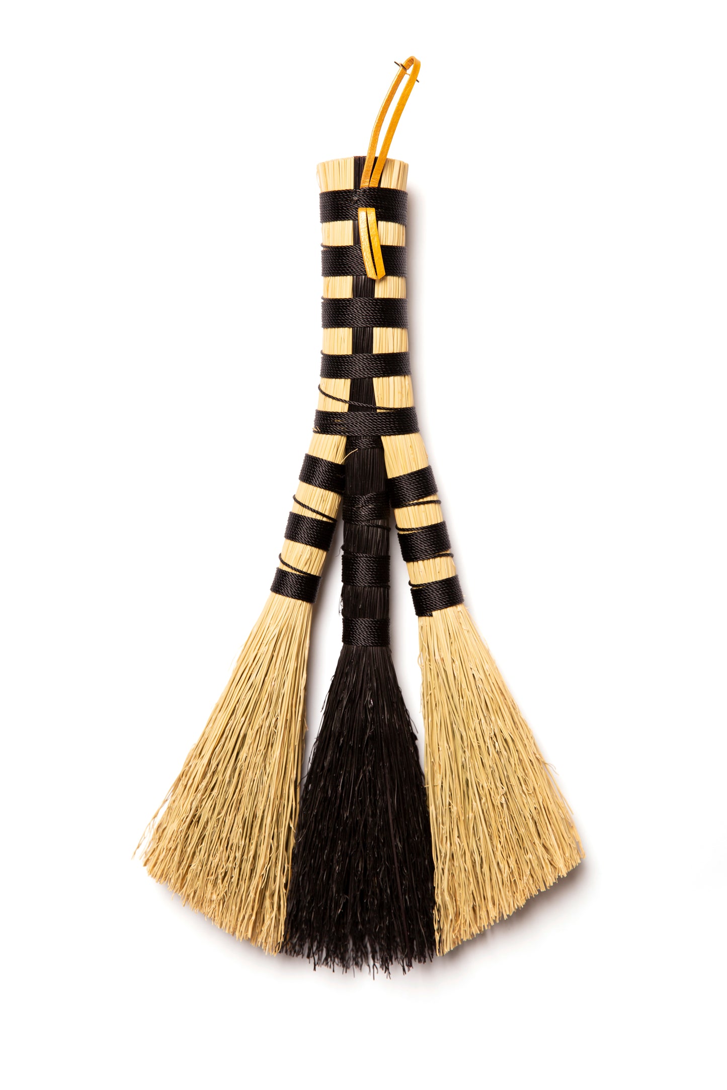 Decorative broom with black and beige bristles on a white background