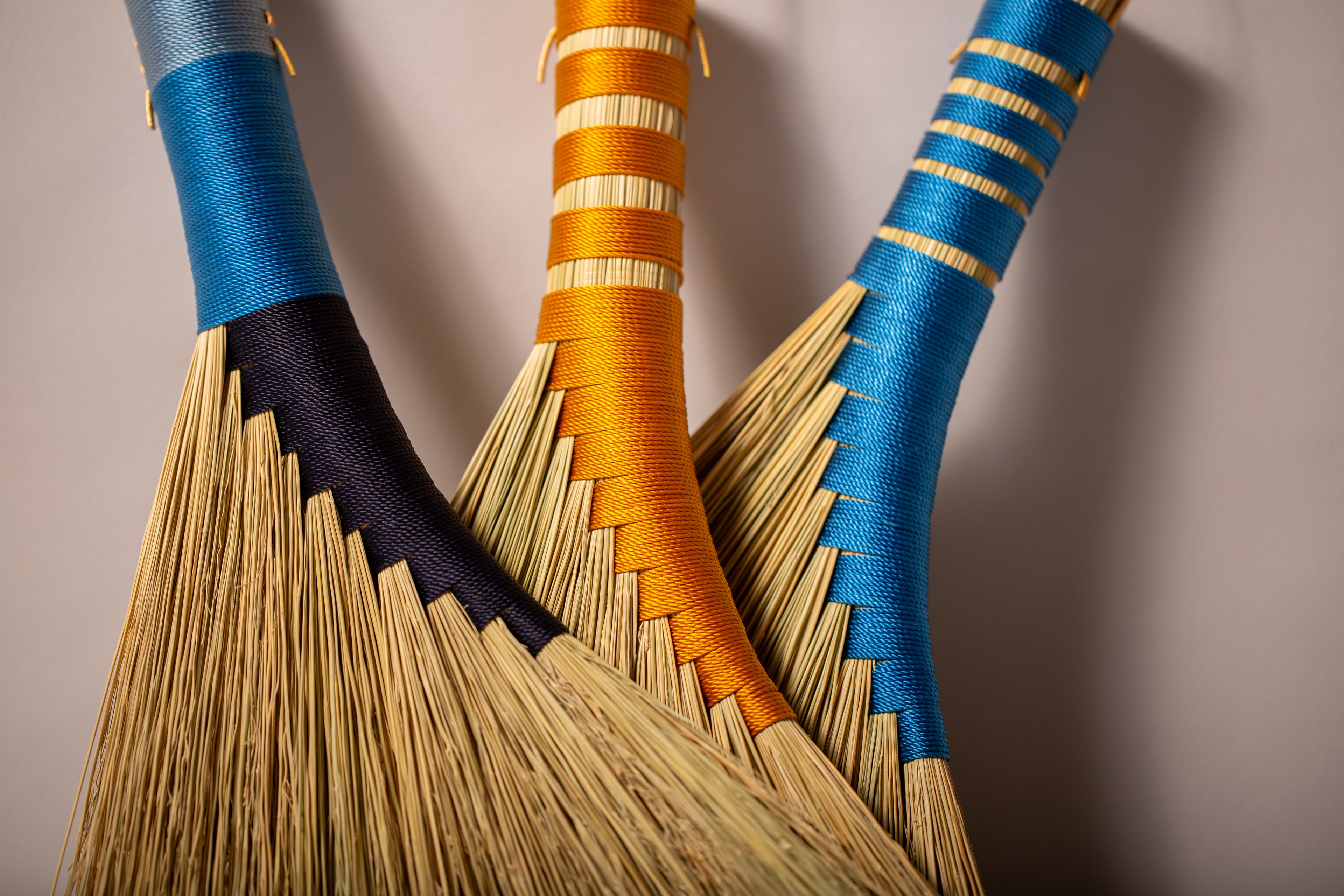 Three hens wings hand brooms in blues and gold twines and natural broomcorn