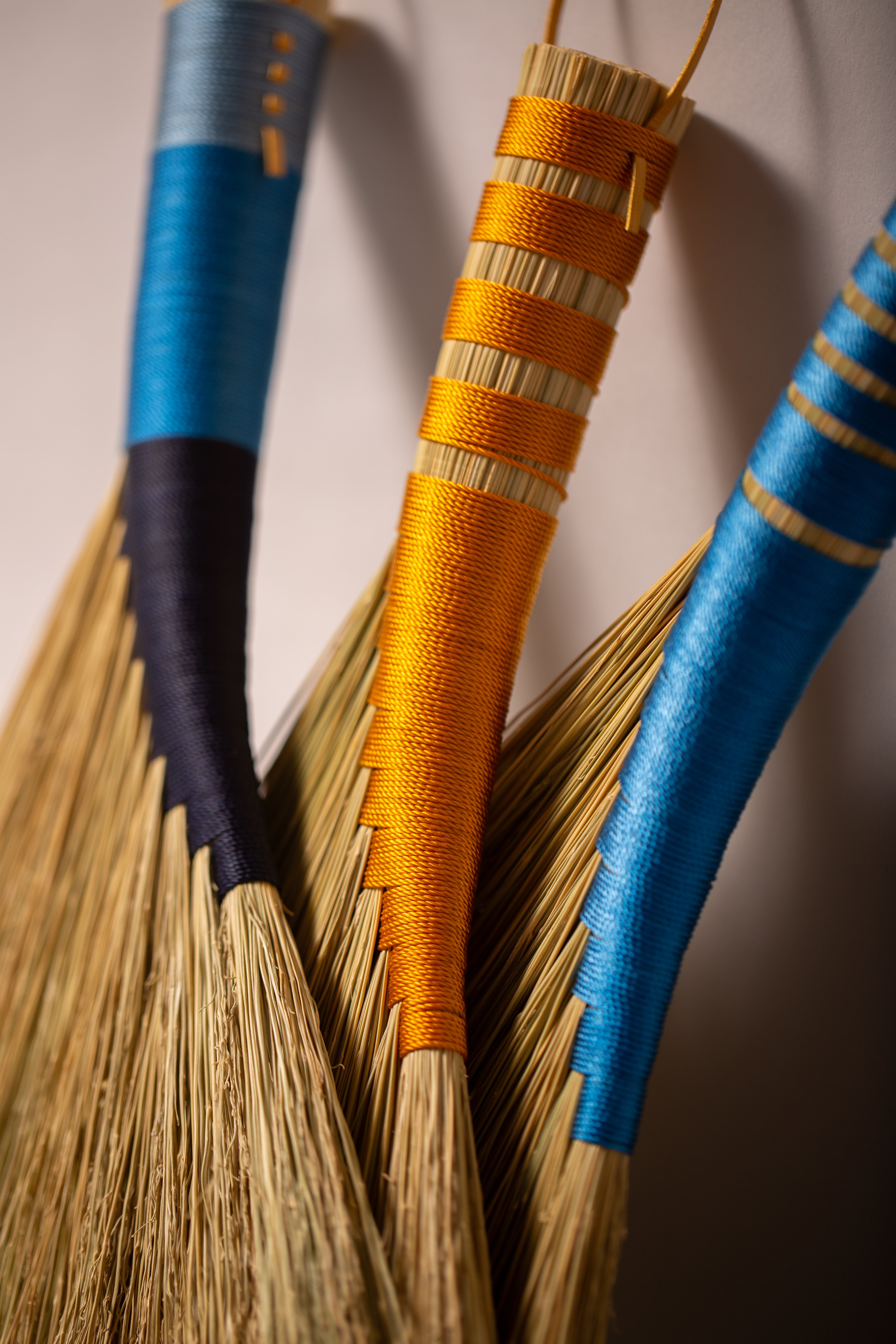 Three hens wings hand brooms in blues and gold twines and natural broomcorn
