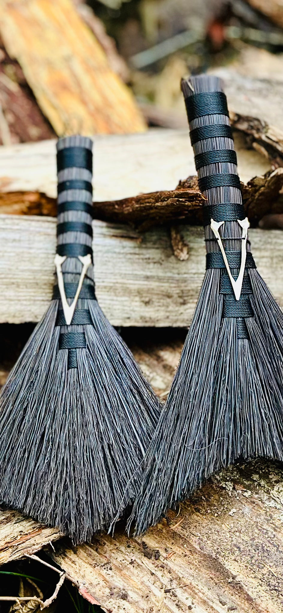 two complimentary handbrooms with crow jaw bones attached black broomcorn and black twines