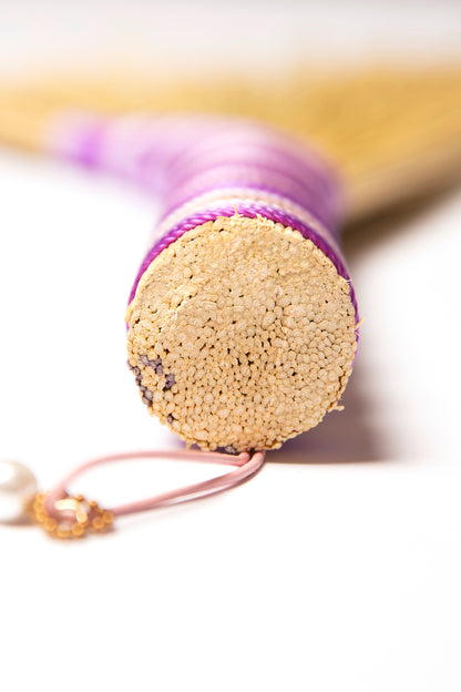View of a hand broom handle wrapped in purple twine against a white background