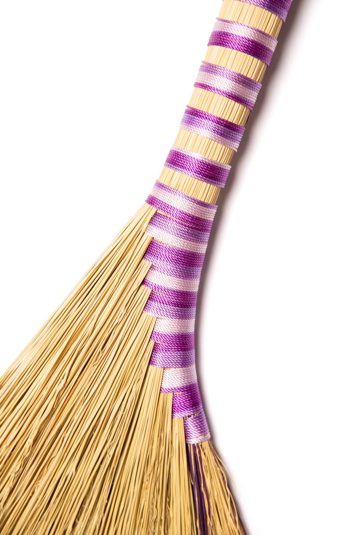 View of a hand broom in purple twine against a white background
