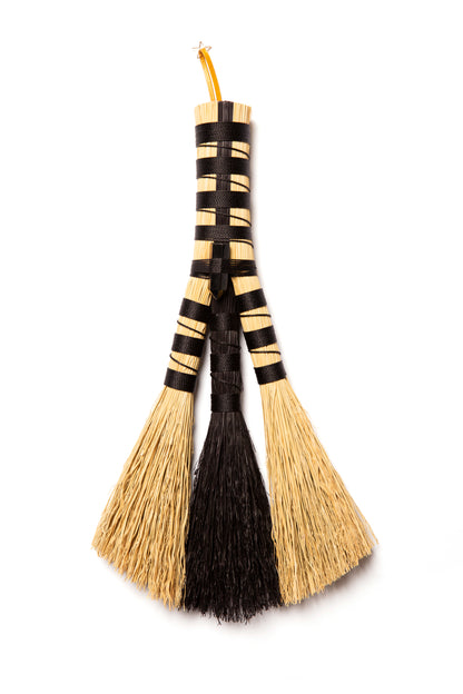 Natural and black broomcorn hand broom against a white background
