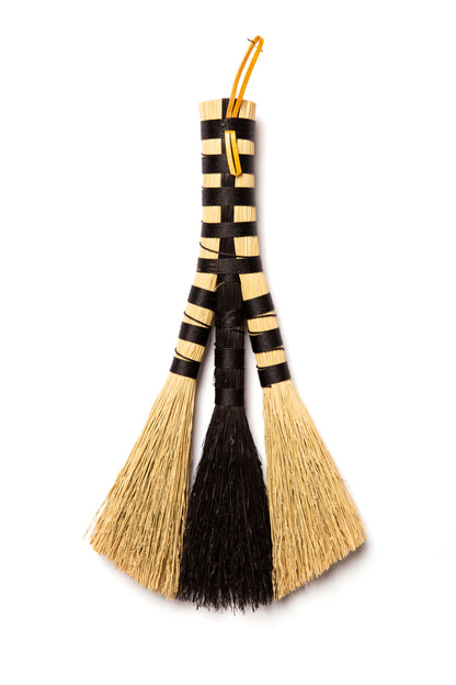 Decorative broom with black and beige bristles on a white background