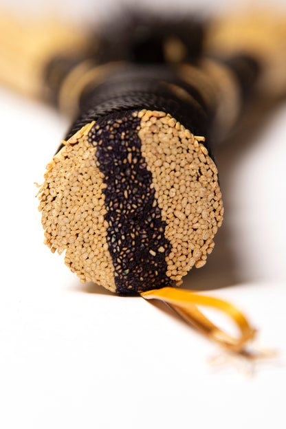 Close-up of a black and natural hand broom handle with gold leather hanger on a white background