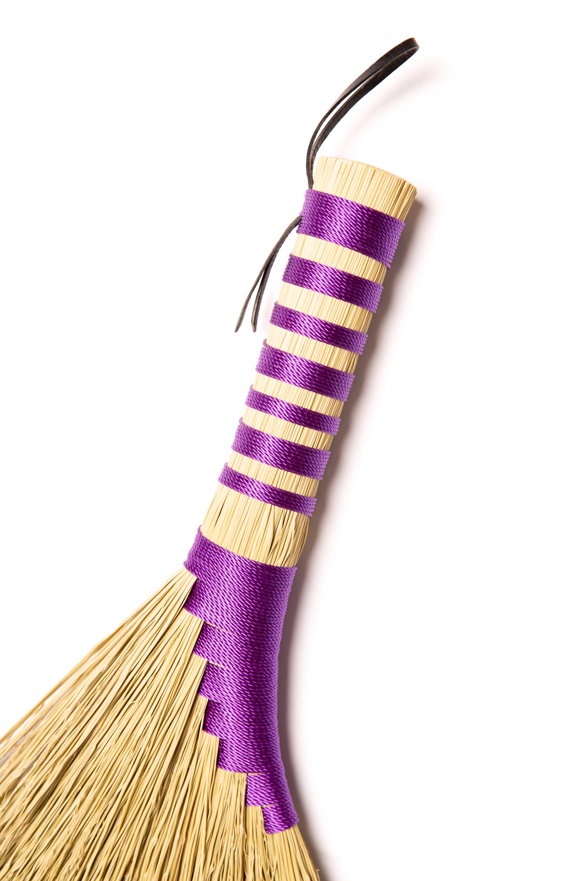 Broom with purple twine on a white background