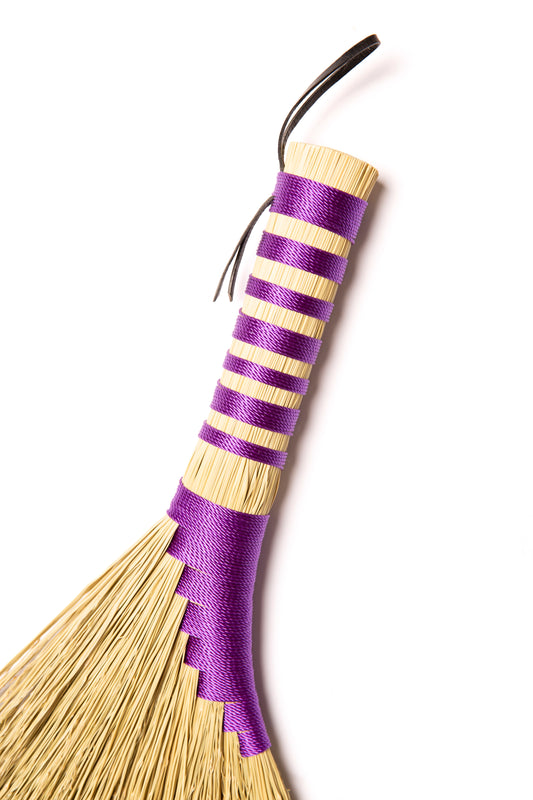 Broom with purple twine on a white background