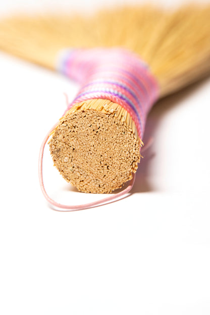 Close-up of a wooden broom handle with a pink band on a white background