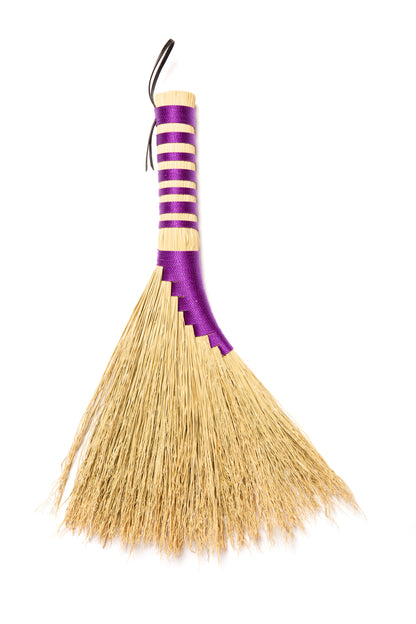 Broom with purple handle and natural broomcorn on a white background