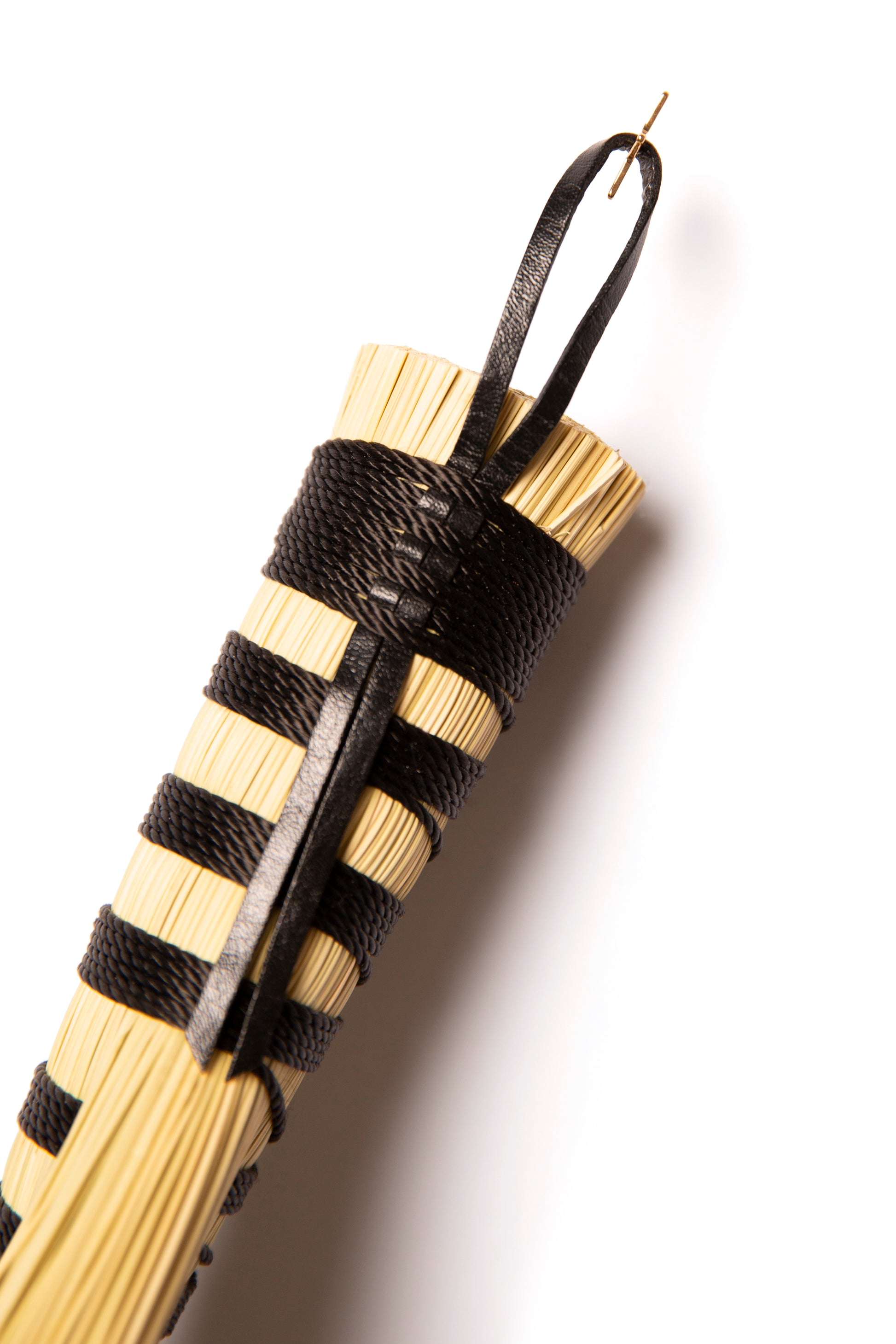 Hand broom handle wound in black twine with natural broomcorn against a white background